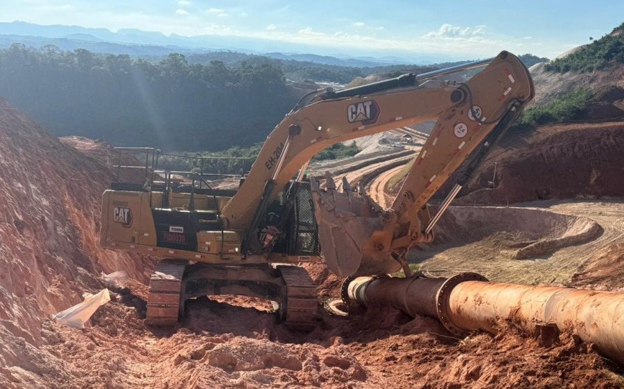 Escavadeira posicionando tubulação na obra da Fidens